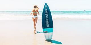 A woman in a bikini runs along the beach, leaving a surfboard behind, with waves crashing and the phrase "Get Lost Into The Blue" visible.