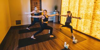 A hand forms a meditation gesture, resting on a yoga mat, surrounded by a serene environment and fitness materials. Peaceful ambiance.